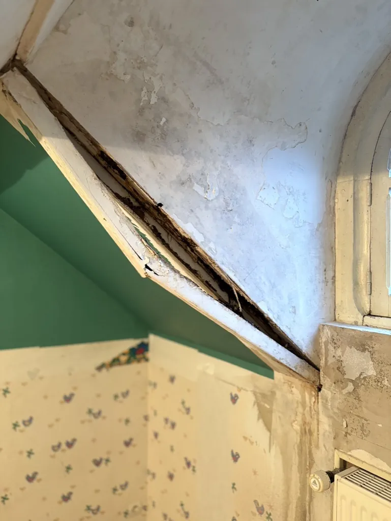 Jambe de force de charpente attaquée par l'humidité dans une chambre